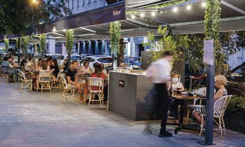 Un camarero atiende a dos clientas en una de las terrazas de veladores  del barrio de Ibiza