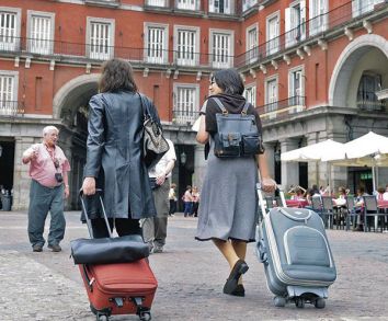 Dos turistas recorren con sus maletas la Plaza Mayor