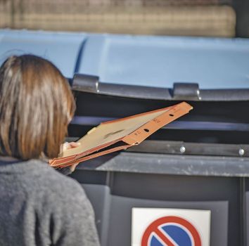 Imagen de una persona reciclando una caja de cartn en el contenedor azul